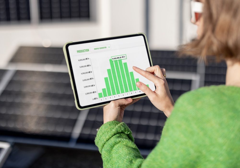 Young woman monitors energy production from the solar power plant with a digital tablet. View on tablet screen with running program. Concept of new technologies in alternative energy