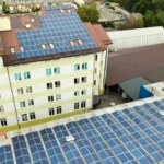 Imagem de vista aérea de painéis solares em prédio de escritórios e unidade fabril.